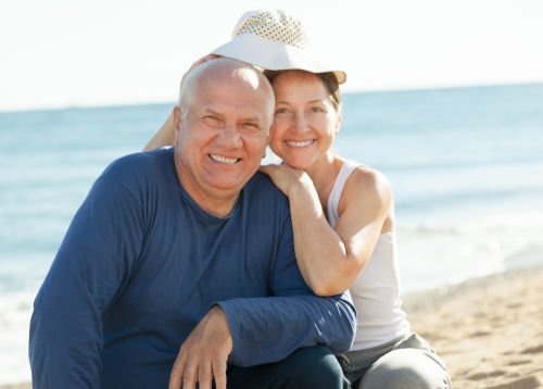 Dental Implants and Bridges | Elderly couple smiling at the beach.