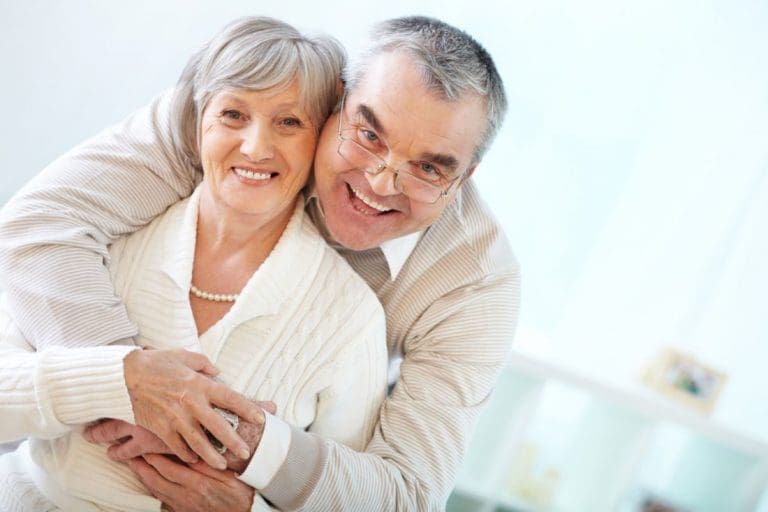Dental Implant Dentist | Happy elderly couple hugging.